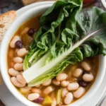 A bowl of steaming escarole and bean soup served with crusty bread.